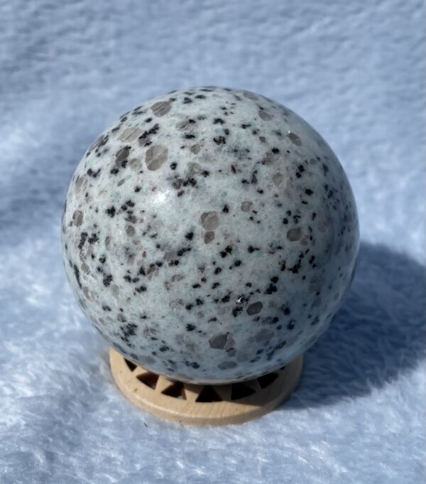 Kiwi jasper sphere on soft blue surface